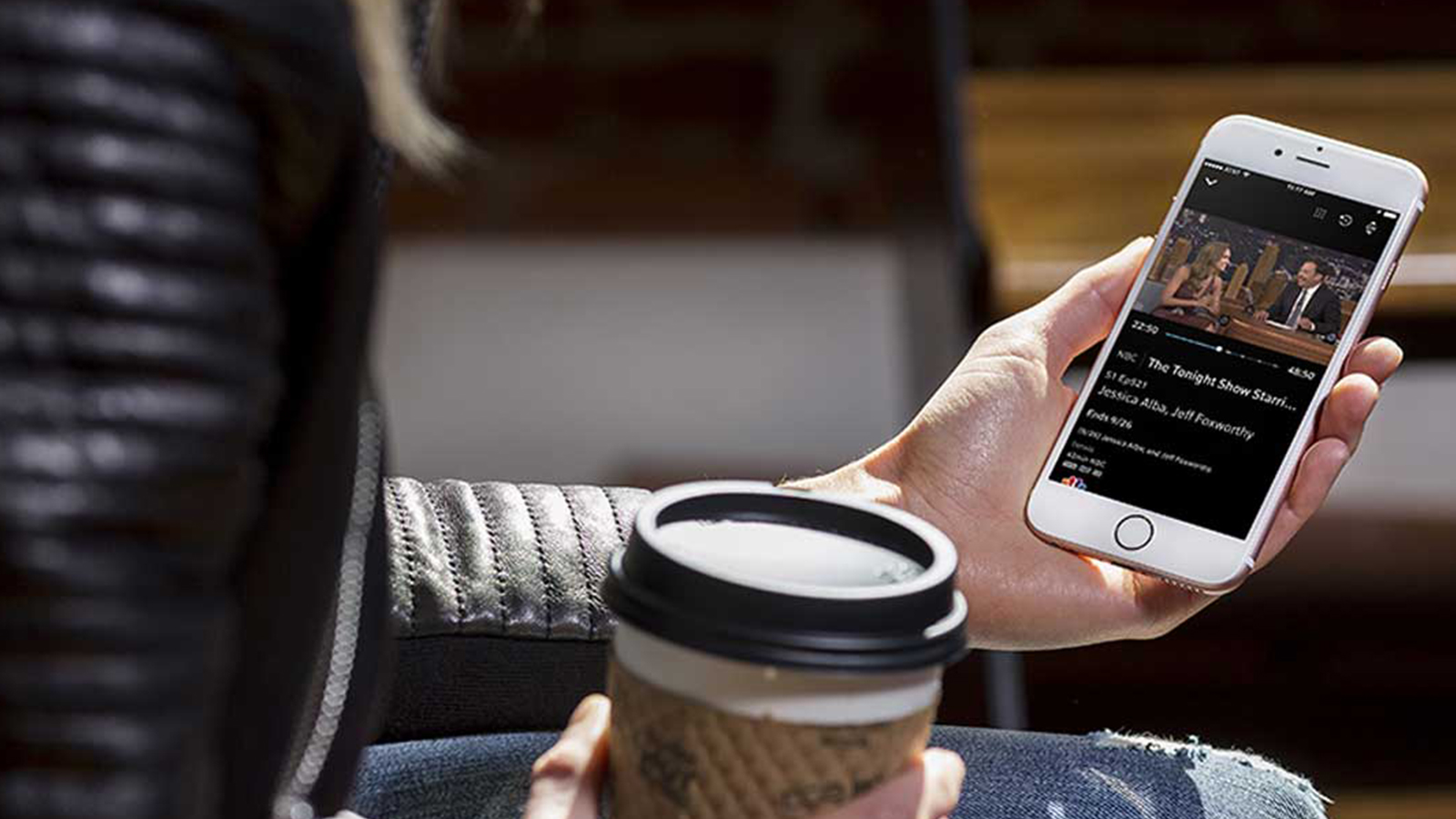 A person uses their mobile phone in a coffee shop.