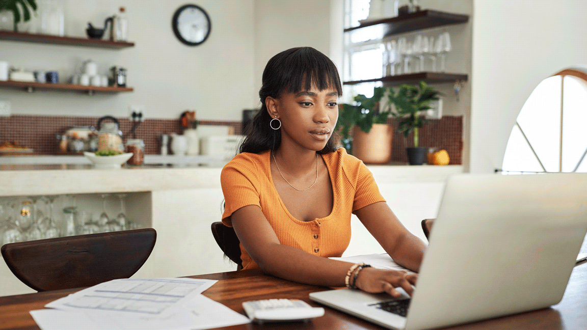 A young woman uses a laptop and calculator