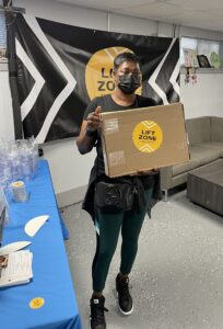 A student holding a free laptop during a Lift Zones event.