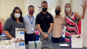 Shawn Perry posing with workers at ACP booth at a recent community center even